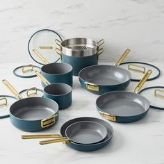 a set of blue pots and pans with gold handles on a marble countertop