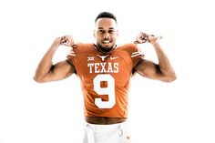 a man in an orange and white football uniform holding his hands up to the side