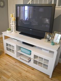 a flat screen tv sitting on top of a white entertainment center in a living room