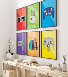 four colorful video game controllers are hanging on the wall above a wooden table with two vases