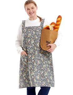 a woman in an apron holding a baguette with bread on it's side