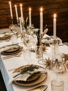 a table set with candles, plates and silverware