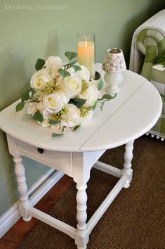 a white table with flowers on it and a candle in the corner next to it