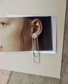 a pair of ear clips sitting on top of a piece of paper next to an image of a woman's face