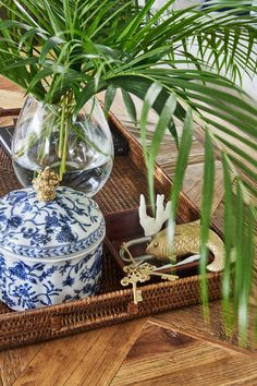 a blue and white vase sitting on top of a table next to a potted plant