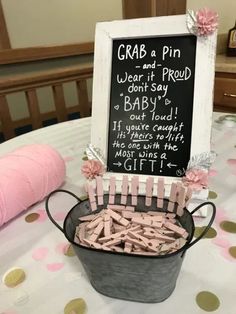 a bucket filled with baby clothes sitting on top of a table next to a chalkboard