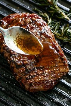 a spoon is being used to stir steak on the grill