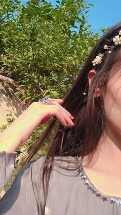 a woman with long hair wearing a flower headband and holding her hand up to her ear