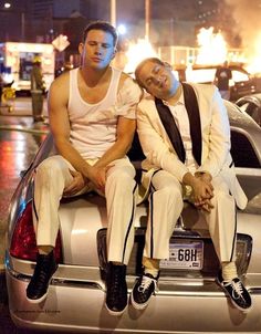 two men sitting on the back of a car