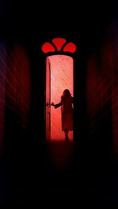 a woman standing in front of a door with red light coming from the top and bottom