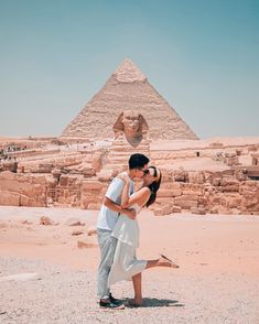 a man and woman kissing in front of the pyramids