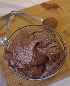 a bowl filled with chocolate frosting on top of a wooden cutting board