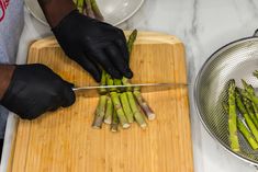 a person cutting asparagus on a cutting board