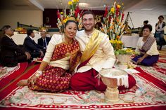 a man and woman sitting on the floor in front of a table full of flowers