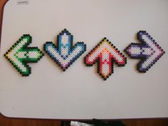 four cross stitched magnets sitting on top of a white board