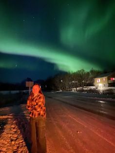 a man standing on the side of a road under an aurora light