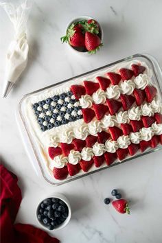 an american flag cake with strawberries and blueberries in the middle on a marble table