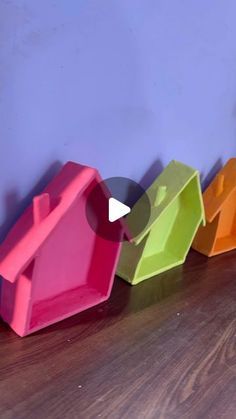 colorful bird houses lined up against a blue wall on a wooden floor in front of a purple wall