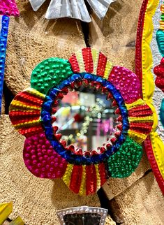 a colorful flower shaped mirror hanging on the side of a wall next to other decorations