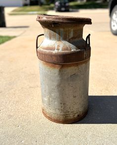 an old rusted can sitting on the sidewalk