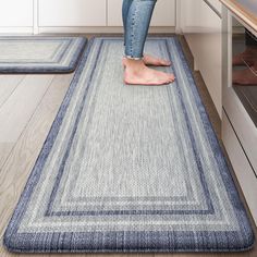 a woman standing on top of a blue rug in a kitchen next to an oven