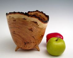 a wooden bowl sitting next to an apple