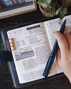 a person is holding a pen and taking notes on a book with an open notebook