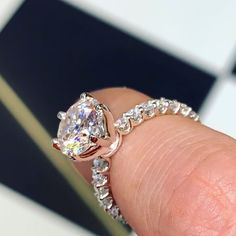 a close up of a person's hand holding a diamond ring