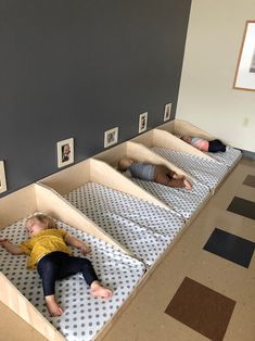 three children laying on mattresses in the middle of a room with pictures on the wall