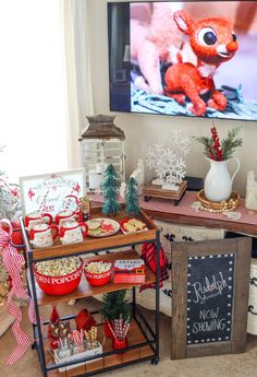 a christmas dessert bar with candy, cookies and other holiday treats on the table in front of a television