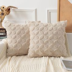 two white pillows sitting on top of a bed next to a vase with flowers in it