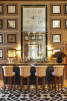 a bar with four stools in front of it and framed pictures on the wall