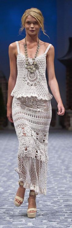 a woman is walking down the runway in a white crochet dress and sandals