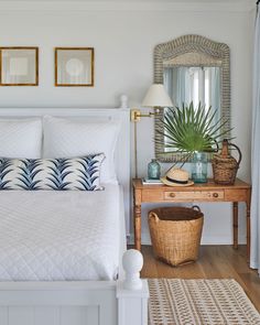 a white bed sitting next to a wooden table with a mirror on top of it