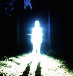 a person standing in the dark with their head turned to the side and light shining on them