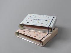 three notebooks stacked on top of each other with the cover pulled open to reveal an image