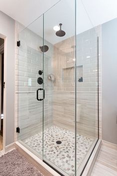 a walk in shower sitting next to a bathroom sink and toilet paper on the floor