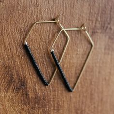 two pairs of black and gold earrings sitting on top of a wooden table