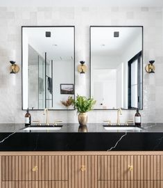 a bathroom with two sinks and mirrors on the wall next to each other in front of a large mirror