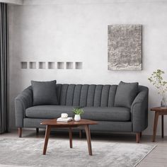 a living room with a gray couch and coffee table in front of the window, next to a painting on the wall