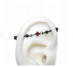 a white sculpture with black beads and a red bead on it's end