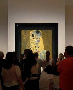 a group of people standing in front of a painting on display at an art museum