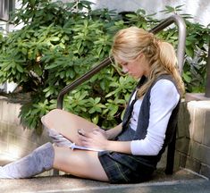 a woman sitting on the ground with her legs crossed and holding a book in front of her