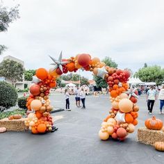 an arch made out of balloons and pumpkins in the middle of a parking lot