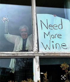 an old man holding a wine bottle in his hand while standing behind a window with a sign that says need more wine