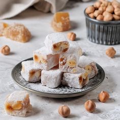 several pieces of dessert on a plate with nuts scattered around it and in the background