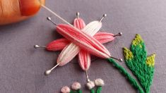 someone is stitching something on the fabric with pins and needles to make a flower brooch