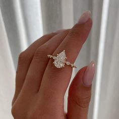 a woman's hand holding a ring with a diamond on it and the middle finger