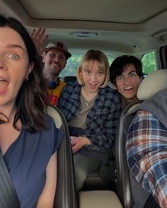 four people sitting in the back seat of a car with their mouths open and one person sticking his tongue out