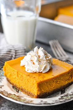 a slice of pumpkin cheesecake on a plate with whipped cream and a glass of milk